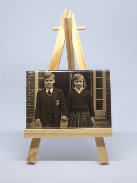 Vintage photograph of children displayed on a wooden stand against a light blue wall.