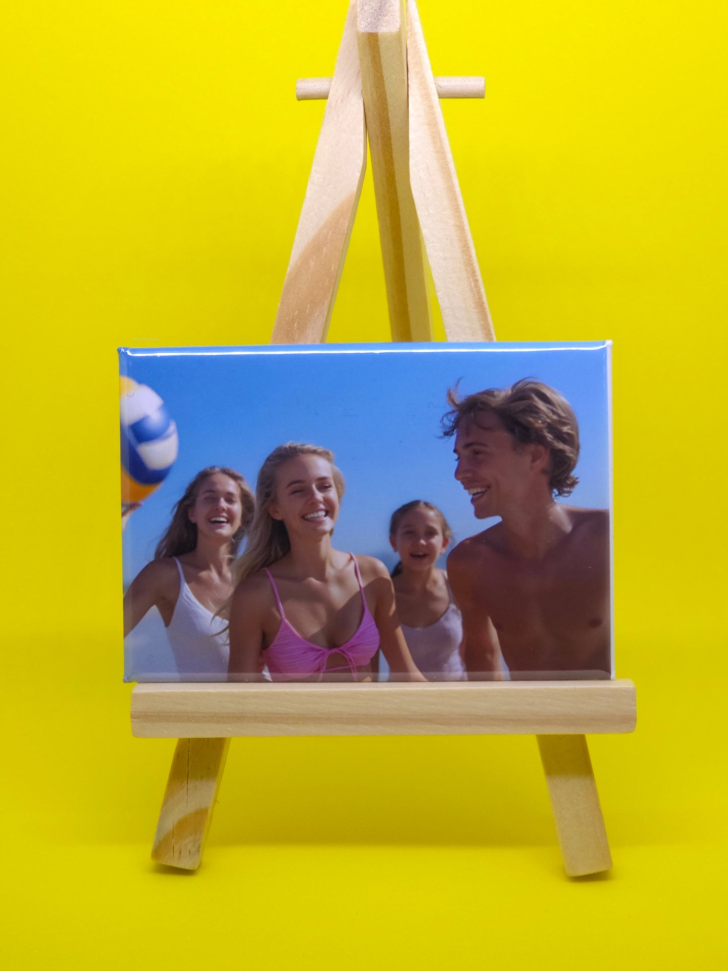 Wooden photo frame with a beach scene of three people on a yellow background