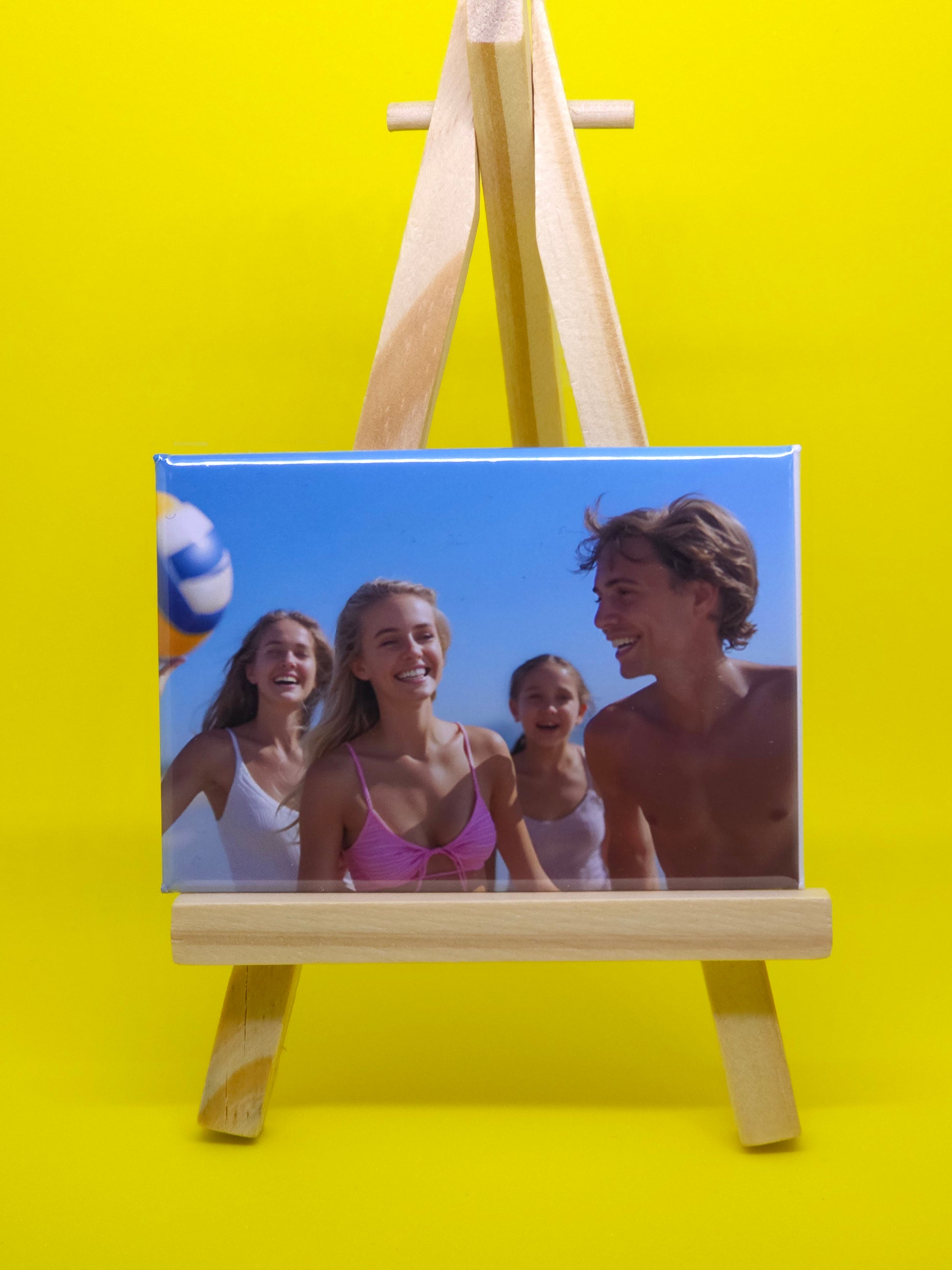 Wooden photo frame with a beach scene of three people on a yellow background