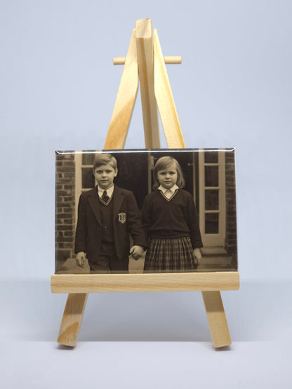 Vintage photograph of children displayed on a wooden stand against a light blue wall.